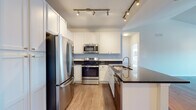 Located at 500 S Third St in Geneva, IL, this single-floor residence offers a thoughtfully designed layout with modern finishes throughout. The kitchen is a standout feature, showcasing white shaker-style cabinetry — including tall pantry-style storage units — paired with dark granite countertops and a full suite of stainless steel appliances, including a French door refrigerator, electric range, and built-in microwave. Track lighting illuminates the space, and a peninsula with a double sink adds both functionality and style. Light wood-tone flooring runs through the main living areas, complementing the clean, neutral color palette. The living area benefits from vaulted ceilings that lend an open, airy feel to the space. Bedrooms are carpeted and filled with natural light from multiple windows, with one bedroom featuring a ceiling fan and views to the exterior. The bathrooms are finished with granite-topped white vanities and tile flooring. One bathroom offers a soaking tub and shower combination, while another features a glass-enclosed walk-in shower. The overall ambiance is bright, clean, and move-in ready, making this Geneva residence a well-rounded and functional home.