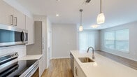 This well-appointed 2-bedroom, 3-bathroom residence at 83 Pleasant Valley St in Methuen, MA offers a thoughtfully designed single-floor layout with modern finishes throughout. The open-concept kitchen and living area serves as the heart of the home, featuring a large center island with a crisp white quartz countertop, undermount sink, and pendant lighting. The kitchen is equipped with stainless steel appliances, including a refrigerator, range, and microwave, complemented by taupe cabinetry and a subway tile backsplash. Warm hardwood-style flooring runs throughout the main living areas, while the living room benefits from a sliding glass door and multiple windows that fill the space with natural light. Both bedrooms are carpeted and offer generous windows with blinds, creating a comfortable and well-lit retreat. The primary bedroom includes a walk-in closet with wire shelving for practical storage. The three bathrooms are finished with clean, contemporary details — including large-format tile flooring, white quartz vanities with wood-tone cabinetry, and a tiled tub-shower combination featuring classic white subway tile. The overall aesthetic is bright, neutral, and move-in ready, reflecting a clean modern design sensibility.