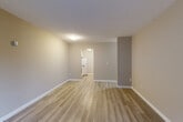 This 1-bedroom, 1-bathroom apartment in Surrey, BC offers a practical and well-organized single-level layout. Light-toned laminate flooring runs throughout the unit, creating a cohesive and easy-to-maintain interior. The entry hallway provides a welcoming transition into the main living areas and includes key hooks for added convenience.

The living room is a bright, open space featuring a large sliding glass door that leads directly to a private balcony, allowing natural light to fill the room and offering outdoor views of the surrounding greenery. Neutral warm-toned walls complement the flooring throughout.

The kitchen is efficiently designed in a galley layout, featuring white cabinetry with brushed nickel hardware, dark granite-style countertops, a tile backsplash, and a full-size refrigerator. Adjacent pantry and closet spaces provide additional storage.

The bedroom is a well-proportioned, quiet room with a window overlooking the exterior, a baseboard heater, and a closet for storage. The bathroom includes a soaker tub with tiled surround, a toilet, and a vanity with dark countertop and an integrated sink. A textured ceiling is present throughout the unit, adding a classic character to the space.