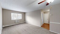 Located at 680 Smith Ct in Rocky River, OH, this one-bedroom, one-bathroom unit offers a practical and efficient single-floor layout. The living room is a welcoming, carpeted space featuring a ceiling fan with light fixture and a wall-mounted air conditioning unit. Natural light filters in through windows with views of surrounding trees, lending a calm, connected-to-nature feel. Baseboard heating runs throughout the carpeted rooms, providing consistent warmth. Neutral taupe walls and clean white trim create a cohesive, understated palette throughout. The layout transitions from the carpeted living and bedroom areas to hardwood flooring in the hallway, adding a touch of warmth and contrast. The bedroom is a well-proportioned, quiet retreat, also carpeted and equipped with its own window and baseboard heating. Three closets distributed throughout the unit offer generous storage options. The bathroom is functional and tidy, featuring a full soaking tub with white tile surround. The kitchen rounds out the unit with essential appliances. Overall, the space maintains a clean, simple aesthetic well-suited for straightforward, comfortable living in a suburban Rocky River setting.