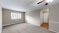 Located at 680 Smith Ct in Rocky River, OH, this one-bedroom, one-bathroom unit offers a practical and efficient single-floor layout. The living room is a welcoming, carpeted space featuring a ceiling fan with light fixture and a wall-mounted air conditioning unit. Natural light filters in through windows with views of surrounding trees, lending a calm, connected-to-nature feel. Baseboard heating runs throughout the carpeted rooms, providing consistent warmth. Neutral taupe walls and clean white trim create a cohesive, understated palette throughout. The layout transitions from the carpeted living and bedroom areas to hardwood flooring in the hallway, adding a touch of warmth and contrast. The bedroom is a well-proportioned, quiet retreat, also carpeted and equipped with its own window and baseboard heating. Three closets distributed throughout the unit offer generous storage options. The bathroom is functional and tidy, featuring a full soaking tub with white tile surround. The kitchen rounds out the unit with essential appliances. Overall, the space maintains a clean, simple aesthetic well-suited for straightforward, comfortable living in a suburban Rocky River setting.