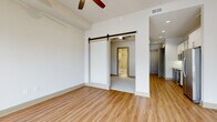 Located in the heart of Midtown Atlanta at 782 Peachtree St NE, this modern single-floor unit combines contemporary finishes with an urban lifestyle. The kitchen is thoughtfully designed with white shaker cabinetry, glass-front upper cabinets, granite countertops, a gray subway tile backsplash, and a full suite of stainless steel appliances, including a smooth-top range, built-in microwave, dishwasher, and French door refrigerator. Light wood-tone flooring flows throughout the main living areas, adding warmth to the clean, neutral palette. The living area is anchored by floor-to-ceiling sliding glass doors and transom windows that fill the space with natural light and open to a private balcony, offering striking views of the Midtown Atlanta skyline. The bedroom features a stylish sliding barn door that leads to an en-suite bathroom, which is finished with tile flooring, a granite-topped vanity, and a tub-shower combination with large-format tile surround. A second carpeted room provides flexible use as a bedroom or office. Ceiling fans are present in the main living and bedroom areas for added comfort. The open, airy layout and city views make this a compelling urban residence in one of Atlanta's most vibrant neighborhoods.