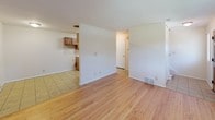 Located at 8037 N 64th St in Brown Deer, Wisconsin, this two-floor residence offers a straightforward and functional layout with consistent design elements throughout. Warm-toned hardwood flooring flows through the living areas and bedrooms, lending a cohesive and clean aesthetic to the interior. The living area transitions smoothly into the kitchen zone, where a distinction in flooring marks the shift to light-toned ceramic tile. The kitchen is well-appointed with abundant warm wood cabinetry wrapping around in a U-shaped configuration, providing generous storage and counter space. A dishwasher and sink are integrated into the layout, and overhead flush lighting keeps the space well-lit.

Multiple rooms across both floors feature windows dressed with vertical blinds, allowing natural light to filter in while maintaining privacy. Baseboard heating units are present in several rooms, providing efficient climate control. The bathrooms include a full bath with a tiled tub-shower surround and white fixtures, as well as a separate half bath featuring a pedestal sink, vanity mirror with overhead lighting, and tile flooring. Throughout the home, neutral white walls and clean white trim create a bright, move-in ready atmosphere suited for a variety of furnishing styles.