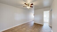 This single-story 3-bedroom, 1-bathroom home offers a practical and well-organized layout across its single floor. Wood-look plank flooring runs consistently throughout, lending warmth and visual continuity to every room. Each bedroom is equipped with a ceiling fan with light kit, providing both comfort and illumination. The spacious primary bedroom stands out as the largest room in the home, offering ample space for furnishings. The two additional bedrooms each feature a built-in closet with shelving and a window that allows natural light to brighten the space. A hallway connects the bedrooms to the shared full bathroom, which is finished in crisp white tones with tile-style flooring, a tub-shower combination, and a window for ventilation. The kitchen, visible in the floor plan view, features a white gas range and refrigerator. One bedroom includes a window-mounted air conditioning unit and direct exterior door access. Throughout the home, clean white walls, white trim, and consistent flooring create a cohesive, move-in-ready aesthetic. The efficient floor plan makes practical use of every square foot, making this home a functional option for those seeking straightforward, low-maintenance living.