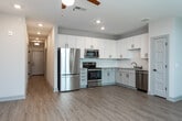Located in Charleston, South Carolina, this single-floor residence combines modern finishes with a clean, functional layout. The open-concept living area is bright and welcoming, featuring light wood-look flooring and a ceiling fan with recessed lighting. Large windows invite an abundance of natural light, offering views of the surrounding greenery and creating an airy atmosphere throughout.

The kitchen is a standout feature, outfitted with crisp white shaker-style cabinetry, granite countertops, a subway tile backsplash, and a full suite of stainless steel appliances including a refrigerator, range, built-in microwave, and dishwasher. Ample counter and cabinet space make this kitchen both practical and visually appealing.

The bedroom is carpeted for comfort and includes a ceiling fan, a window with natural light, and access to a spacious walk-in closet equipped with wire shelving systems for organized storage. The bathroom is well-appointed with wood-look tile flooring, a granite-topped vanity with gray cabinetry, matte black hardware accents, and a tiled tub-shower combination. Panel-style doors with matte black hardware are featured throughout, adding a cohesive, contemporary touch to the overall design of this Charleston residence.