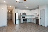 Located in Charleston, South Carolina, this single-floor residence combines modern finishes with a clean, functional layout. The open-concept living area is bright and welcoming, featuring light wood-look flooring and a ceiling fan with recessed lighting. Large windows invite an abundance of natural light, offering views of the surrounding greenery and creating an airy atmosphere throughout.

The kitchen is a standout feature, outfitted with crisp white shaker-style cabinetry, granite countertops, a subway tile backsplash, and a full suite of stainless steel appliances including a refrigerator, range, built-in microwave, and dishwasher. Ample counter and cabinet space make this kitchen both practical and visually appealing.

The bedroom is carpeted for comfort and includes a ceiling fan, a window with natural light, and access to a spacious walk-in closet equipped with wire shelving systems for organized storage. The bathroom is well-appointed with wood-look tile flooring, a granite-topped vanity with gray cabinetry, matte black hardware accents, and a tiled tub-shower combination. Panel-style doors with matte black hardware are featured throughout, adding a cohesive, contemporary touch to the overall design of this Charleston residence.