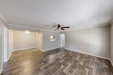 This single-floor home offers a practical and well-designed layout across two bedrooms and two bathrooms. The living room serves as the welcoming centerpiece of the home, featuring rich wood-look flooring, crown molding, a textured ceiling, and a ceiling fan that enhances air circulation and ambiance. Large windows with blinds allow natural light to fill the space, creating a bright and airy atmosphere. The kitchen is efficiently designed with white cabinetry, speckled stone countertops, black appliances including a refrigerator and dishwasher, and wood-look flooring that ties seamlessly into the main living area. A pendant light fixture adds a finishing touch to the kitchen's clean aesthetic. Both bedrooms are carpeted for comfort and feature neutral-toned walls, windows with blinds for natural light, and closet storage. The primary bedroom offers a generous footprint, providing ample space for furnishings. Each bathroom is finished with wood-look flooring, a full tub-shower combination with white tile surround, brushed nickel fixtures, and speckled stone vanity countertops. The overall design palette of soft neutral tones and consistent flooring choices gives the home a cohesive, move-in-ready feel.