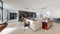 Located at 567 North Ave NE in Atlanta's vibrant Old Fourth Ward neighborhood, this single-floor space showcases a sleek, contemporary design defined by soaring ceilings, an open-plan layout, and abundant natural light throughout. The herringbone-patterned tile flooring flows seamlessly across the entire space, unifying each functional area with a cohesive, refined aesthetic.

The kitchen is a standout centerpiece, anchored by a large waterfall-edge marble island with seating for multiple guests. Matte sage-green cabinetry lines the perimeter walls, complemented by a geometric white tile backsplash, stainless steel appliances, and a built-in microwave. Sculptural pendant lights with bronze and cone-shaped elements hang overhead, adding an artistic touch.

Adjacent to the kitchen, a dedicated dining area features booth-style seating set against a warm cork accent wall, creating an intimate yet stylish setting. A vibrant painting adds a focal point to this corner of the space.

The living area is expansive and light-filled, with a wall of floor-to-ceiling windows offering outdoor views. A dramatic built-in entertainment wall with angular shelving and dark matte finishes anchors the room, while plush sectional seating and layered rugs create an inviting atmosphere. The overall ambiance is modern, sophisticated, and thoughtfully designed for both comfort and visual impact.