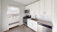 Located at 555 Main St in Chatham, NJ, this 2-bedroom, 1-bathroom residence offers a clean, modern aesthetic with thoughtful updates throughout. The layout flows across a single floor, connecting well-proportioned living spaces finished with durable hardwood-style flooring and neutral gray-toned walls that create a bright, inviting atmosphere.

The kitchen stands out with its white shaker cabinetry, white subway tile backsplash, and stainless steel appliances including a gas range, over-the-range microwave, and dishwasher. A single-basin sink, ample counter space, and a window overlooking the outdoors complete the functional yet stylish kitchen.

Both bedrooms are generously sized, each featuring hardwood-style flooring, large windows that invite natural light, and baseboard heating units. One bedroom includes a spacious sliding-door closet with a hanging rod for convenient storage.

The living area is open and airy, with multiple windows and a window-unit air conditioner. A dedicated entryway with a solid white door provides a welcoming transition into the home.

The bathroom is finished with wood-look tile flooring, a white vanity, and a tub-shower combination accented by full-height marble-style subway tile, offering a clean and refined look. A window adds natural light to the space.