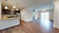 Located at 2150 Bond St in Charlottesville, VA, this single-floor residence offers a thoughtfully designed open-concept layout that seamlessly connects the kitchen, dining, and living areas. Rich hardwood-style flooring runs throughout the main living spaces, complemented by crown molding and recessed lighting that enhance the clean, contemporary aesthetic.

The kitchen is a standout feature, equipped with dark espresso cabinetry, light granite countertops, stainless steel appliances including a refrigerator, microwave, and dishwasher, and a peninsula with an integrated sink — ideal for both meal prep and casual dining. Pendant lighting above the peninsula adds a refined finishing touch.

The living area is generously sized, bathed in natural light from a sliding glass door that leads to a private balcony. A ceiling fan provides year-round comfort. Bedrooms are carpeted for warmth and comfort, with one featuring a window that brings in additional natural light and outdoor views.

The bathrooms are finished with wood-look tile flooring and clean white fixtures. One bathroom includes a tub-shower combination with white subway tile surround, while another features a dark vanity with granite countertop and a large mirror. The entry foyer provides ample closet storage, completing this well-appointed and functional home.