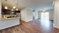 Located at 2150 Bond St in Charlottesville, VA, this single-floor residence offers a thoughtfully designed open-concept layout that seamlessly connects the kitchen, dining, and living areas. Rich hardwood-style flooring runs throughout the main living spaces, complemented by crown molding and recessed lighting that enhance the clean, contemporary aesthetic.

The kitchen is a standout feature, equipped with dark espresso cabinetry, light granite countertops, stainless steel appliances including a refrigerator, microwave, and dishwasher, and a peninsula with an integrated sink — ideal for both meal prep and casual dining. Pendant lighting above the peninsula adds a refined finishing touch.

The living area is generously sized, bathed in natural light from a sliding glass door that leads to a private balcony. A ceiling fan provides year-round comfort. Bedrooms are carpeted for warmth and comfort, with one featuring a window that brings in additional natural light and outdoor views.

The bathrooms are finished with wood-look tile flooring and clean white fixtures. One bathroom includes a tub-shower combination with white subway tile surround, while another features a dark vanity with granite countertop and a large mirror. The entry foyer provides ample closet storage, completing this well-appointed and functional home.