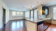 Located at 502 S Post Oak Lane in Houston's prestigious Galleria neighborhood, this single-floor residence offers a thoughtfully designed open-concept layout. The living and dining area is bathed in natural light from a generous bank of windows, complemented by a ceiling fan and rich hardwood flooring that extends throughout the main living spaces.

The kitchen is a standout feature, boasting dark espresso cabinetry, granite countertops, and a full suite of stainless steel appliances including a refrigerator, range, microwave, and dishwasher. Stylish pendant lighting and a track lighting system illuminate the space, while a central island with a sink provides both additional prep space and a natural gathering point.

A well-proportioned hallway connects the main living area to the private quarters, where carpeted bedrooms offer a comfortable retreat. Each bedroom provides generous proportions and easy access to the bathrooms, which are finished with large-format tile flooring, dark-framed mirrors, granite vanity tops, and dark wood cabinetry. Both bathrooms are adjoined by spacious walk-in closets with built-in shelving and hanging rods, providing ample storage throughout the residence.