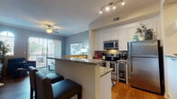 This two-story residence offers a thoughtfully designed layout that balances open communal spaces with private retreats. The main living area features rich hardwood-style flooring, a ceiling fan, and sliding glass doors that invite natural light and provide access to an outdoor balcony. The adjacent kitchen is well-equipped with white shaker cabinetry, granite countertops, stainless steel appliances including a built-in wine cooler, a tile backsplash, and a peninsula with bar seating that connects seamlessly to the living space.

Multiple bedrooms are present throughout the home. One features vaulted ceilings, plush carpeting, and a ceiling fan, while another offers soft neutral tones, a decorative accent wall, and a bright window with outdoor views. The primary bathroom is appointed with dual granite-topped vanities, hardwood-style flooring, a soaking tub, and a separate glass-enclosed shower. A secondary bathroom mirrors the same quality finishes, featuring a granite vanity and hardwood-style flooring. The overall ambiance throughout the home is warm and cohesive, with consistent use of granite surfaces and wood-tone flooring tying each space together.