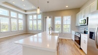 Located at 14355 North Main Street in Jacksonville, FL, this well-appointed single-story home offers 2 bedrooms, 3 bathrooms, and a thoughtfully designed layout ideal for comfortable living. The open-concept kitchen and living area serves as the heart of the home, showcasing soaring ceilings, oversized windows, and expansive outdoor views that flood the space with natural light. The kitchen is a standout feature, equipped with stainless steel appliances, sage green cabinetry, a decorative geometric tile backsplash, a large white quartz island with an undermount sink, and pendant lighting — combining both style and function. The living area continues the bright, airy aesthetic with light wood-look flooring and a tray ceiling detail. The bedrooms are carpeted for comfort, with the primary bedroom offering generous proportions and direct access to a well-sized en-suite. The bathrooms are finished with granite countertops, white shaker cabinetry, and warm wood-look flooring. Additional highlights include a dedicated laundry area, multiple closets for ample storage, an entrance foyer, and a connecting hallway. Throughout, the home maintains a clean, neutral palette with warm tones that create a welcoming and move-in-ready atmosphere.