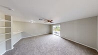 Located at 5601 FM-517 in Dickinson, Texas, this single-story home offers a practical and well-organized layout across two bedrooms, two bathrooms, a combined kitchen and living area, and a hallway. The kitchen is equipped with white shaker-style cabinetry, stainless steel appliances including a refrigerator, microwave, and range, and features a quartz countertop with an undermount sink — providing a clean, modern aesthetic. The living room is a generously sized, open space with soft carpeting, a ceiling fan with integrated lighting, and a sliding glass door that opens to a view of the surrounding greenery and parking area. Both bedrooms are carpeted and outfitted with ceiling fans, offering comfortable and functional spaces filled with natural light through window blinds. The primary bedroom is notably spacious and well-proportioned. Both bathrooms are finished with large-format marble-look ceramic tile surrounding the tub-shower combinations, complemented by brushed nickel fixtures for a polished look. The neutral gray tones used throughout the walls create a cohesive and inviting atmosphere. From the outdoor-facing areas, views of mature trees and open sky add a natural, serene quality to the setting.