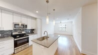 Located at 6306 McNeil Dr in Austin, TX, this single-story, 3-bedroom, 2-bathroom home offers a clean, modern aesthetic defined by bright white walls, light hardwood-style flooring, and an open, functional layout. The kitchen serves as the heart of the home, featuring a central island with a quartz-style countertop, undermount sink, and stylish pendant lighting overhead. White flat-panel cabinetry reaches to the ceiling for ample storage, while a dark tile backsplash adds contrast against stainless steel appliances, including a refrigerator, electric range, and microwave. The kitchen flows seamlessly into the living area, which is bathed in natural light from large windows and finished with a ceiling fan. The three bedrooms are bright and well-proportioned, each with light hardwood-style floors, white walls, and windows fitted with blinds. The primary bedroom offers a comfortable retreat with dedicated closet access. Both bathrooms maintain the home's clean palette, featuring white vanities with brushed nickel hardware, mirrors, and hardwood-style flooring. Two hallways connect the spaces efficiently, and a dedicated closet provides additional storage. The overall ambiance is light, airy, and move-in ready.