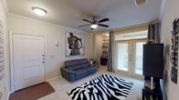 This single-story residence in Tomball, Texas offers a thoughtfully designed layout with one bedroom and one bathroom. The living area serves as the focal point of the home, featuring plush carpeting, crown molding, and a ceiling fan overhead. A set of French doors floods the space with natural light and provides access to the outdoors, while built-in shelving nearby offers functional display and storage options. The entry foyer transitions seamlessly into the living area, creating an open and welcoming atmosphere.

The bedroom is a comfortable retreat, highlighted by crown molding, a ceiling fan, and a window dressed with grommet-panel curtains that allow for natural light. A walk-in closet provides generous storage space. The full bathroom is finished with wood-look flooring, dark cabinetry topped with granite-style counters, and a tub-shower combination with white tile surround. The kitchen, visible in the floor plan, is efficiently positioned adjacent to the living area. Throughout the residence, neutral tones and consistent finishes contribute to a cohesive, move-in-ready aesthetic.