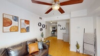 Located at 1834 Jackson Bluff Rd in Tallahassee, FL, this single-floor unit offers a thoughtfully designed layout with a warm, eclectic aesthetic throughout. The living area is a comfortable, well-lit space anchored by light hardwood-style flooring, a ceiling fan, and a sliding glass door that opens to a private outdoor patio, inviting natural light and greenery views inside. The kitchen is outfitted with stainless steel appliances, light wood cabinetry, a mosaic tile backsplash, and track lighting, connecting seamlessly to the living and dining areas. Adjacent to the kitchen, a built-in display niche and a granite-topped wine refrigerator add a stylish, functional touch to the transitional hallway space. The bathroom is well-appointed with wood-look tile flooring, a granite vanity, and a fully tiled walk-in shower with mosaic accent detailing and louvered closet doors. Two bedrooms provide restful retreats—one featuring carpeted floors, a ceiling fan, and vibrant, colorful décor, while the other offers a serene, neutral atmosphere with soft textiles. The overall ambiance of the space is modern yet inviting, blending contemporary finishes with warm, personalized design elements throughout.