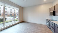Located at 2939 Smallman St, Unit 213, in Pittsburgh's vibrant Strip District, this 470-square-foot, one-bedroom apartment offers a thoughtfully designed single-floor layout. The open-concept living and kitchen area features light wood-tone flooring, recessed lighting, and an exposed metallic ductwork detail that adds an industrial character to the space. The kitchen is equipped with dark espresso cabinetry, a white subway tile backsplash, stainless steel appliances including a refrigerator, electric range, and built-in microwave, along with a single-basin sink. A large sliding glass door in the living area floods the space with natural light and provides views of an outdoor amenity area with a pool. The 100-square-foot bedroom is carpeted and includes access to a dedicated closet, offering practical storage. A hallway connects the main living areas to the bedroom and bathroom. Neutral tones throughout the unit create a clean, modern ambiance. This compact yet functional apartment is well-suited for those seeking contemporary urban living in one of Pittsburgh's most dynamic neighborhoods.