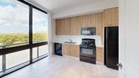 This 310 square foot apartment in Miami offers a compact yet functional living space. The single-floor layout comprises one bedroom, one bathroom, and a kitchen, efficiently designed to maximize the available area. The bedroom, measuring 90 square feet, provides a cozy retreat.

The kitchen is a standout feature, boasting modern wood-grain cabinetry and a full suite of black appliances, including a refrigerator, stove, microwave, and dishwasher. A white backsplash and countertop create a clean contrast against the warm wood tones. Large windows in the kitchen area offer city views and abundant natural light.

Throughout the apartment, light-colored tile flooring enhances the sense of space and brightness. The bathroom, while compact, is well-appointed with a white tub-shower combination, toilet, and vanity. Safety features include a grab bar in the shower area.

The living areas benefit from high ceilings and a modern ceiling fan, contributing to an airy atmosphere. The neutral color palette of whites and light grays provides a blank canvas for personalization. Despite its small footprint, the apartment's thoughtful design and contemporary finishes create a comfortable urban living space in the heart of Miami.