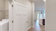 Located at 1 Mossy Grove Ln in Delaware, Ohio, this well-appointed 2-bedroom, 2-bathroom single-story home offers a thoughtfully designed layout with modern finishes throughout. The open-concept kitchen serves as the heart of the home, featuring a large central island with white quartz countertops, rich dark wood cabinetry, stainless steel appliances including a refrigerator and microwave, recessed lighting, and stylish pendant lights. Wood-look luxury vinyl plank flooring extends through the main living and kitchen areas, complementing the neutral warm-toned walls. The living area is bright and airy, with multiple windows providing generous natural light and outdoor views. Both bedrooms are carpeted for comfort, with the spacious primary bedroom offering ample room and access to a dedicated walk-in closet with built-in wire shelving. The primary bathroom includes a double-sink vanity with dark wood cabinetry, white countertops, a glass-enclosed walk-in shower, and wood-look flooring. The second bathroom features a full tub-shower combo and a single vanity with matching finishes. A dedicated laundry room with in-unit washer and dryer hookups and overhead shelving adds everyday convenience. The home's clean, modern aesthetic and functional layout make it a comfortable and practical living space.