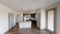 This single-story residence in Grand Prairie, Texas offers a well-designed, open-concept layout with thoughtful finishes throughout. The kitchen serves as the heart of the home, showcasing rich dark cabinetry, granite countertops, and a full suite of stainless steel appliances including a refrigerator, electric range, microwave, and dishwasher. A center island with a granite surface provides additional prep space and casual seating, while pendant lighting and a track light fixture add a modern touch. Dark hardwood-style flooring runs throughout the main living and hallway areas, complementing the neutral, light-toned walls.

The living area is bright and welcoming, with large windows dressed in blinds that frame outdoor views of the surrounding neighborhood's green landscaping. Bedrooms feature plush carpeting, ceiling fans, and windows that invite natural light. The primary bathroom is generously appointed with a dual-sink vanity topped in granite, dark cabinetry, a glass-enclosed walk-in shower with tile surround, and a separate soaking tub. An arched passageway adds an architectural detail that enhances the flow between spaces. A clean, well-lit hallway connects the rooms, completing this functional and attractively finished home.