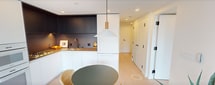First Light - Unit 2404 is a thoughtfully designed one-bedroom, two-bathroom condominium spanning 660 square feet across a single floor. The open-concept living area features light wood flooring, white cabinetry with integrated appliances, and large floor-to-ceiling sliding glass doors that flood the space with natural light. These doors open directly onto a private balcony offering dramatic, unobstructed views of the surrounding city skyline — a standout feature of this high-rise residence.

The bedroom, at 100 square feet, is a bright and minimalist retreat with direct balcony access, expansive city views through floor-to-ceiling glazing, built-in closets, and clean white walls that create a calm, restful atmosphere.

Both bathrooms are finished to a high standard. The primary bathroom features terrazzo-style stone tile on the floors and walls, a soaking tub with matte black fixtures, a wall-mounted toilet, and a glass-enclosed walk-in shower with a rain showerhead. The second bathroom maintains the same refined aesthetic with terrazzo flooring and matte black hardware throughout.

Overall, the unit presents a cohesive modern design language — clean lines, neutral tones, and premium finishes — set against an exceptional urban backdrop.