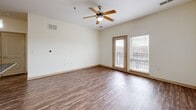 Located at 601 NE 70th St in Gladstone, MO, this one-bedroom, one-bathroom unit is thoughtfully laid out across a single floor. The kitchen is a standout feature, showcasing light wood cabinetry, dark granite-style countertops, a center island with a built-in sink, and a full suite of stainless steel appliances including a refrigerator, range, and over-the-range microwave. Track lighting and pendant lights illuminate the space, which flows directly into the open living area. The living room is finished with rich wood-style flooring, a ceiling fan, and a glass door leading to a private balcony with outdoor views, allowing for excellent natural light. The bedroom is carpeted for comfort, features a ceiling fan, and is brightened by a window overlooking the surrounding area. Two closets provide ample storage throughout the unit. The bathroom is finished with tile flooring, a combined tub and shower, and a wood-toned vanity. Additional practical spaces include a dedicated laundry area, a utility room, and an entrance foyer. The neutral color palette and consistent finishes create a clean, modern ambiance throughout.