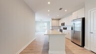 Located at 2020 W Morehead Street in Charlotte, NC, this single-floor residence offers a clean, contemporary design with a bright and functional layout. The open-concept living and kitchen area serves as the heart of the home, featuring light wood-look flooring, recessed lighting, and large windows that invite natural light throughout. A ceiling fan enhances comfort in the living space, which flows seamlessly toward a private patio door.

The kitchen is well-appointed with crisp white cabinetry, a classic subway tile backsplash, quartz countertops, and a generous center island ideal for meal prep or casual dining. Stainless steel appliances — including a range, microwave, and refrigerator — complete the modern aesthetic.

The bedrooms are carpeted for comfort and offer generous proportions. The primary bedroom connects directly to an en-suite bathroom featuring a single-sink vanity with quartz countertops, tile shower, wood-look flooring, and access to a walk-in closet with wire shelving. A second full bathroom mirrors the same refined finishes. A dedicated laundry area with a full-size washer and dryer adds everyday convenience. Overall, the space presents a cohesive, neutral palette suited for modern living in Charlotte's Morehead Street corridor.
