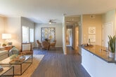 Located at 5700 Lochmoor Dr in Riverside, California, this single-floor residence offers a thoughtfully designed layout that balances comfort and functionality. The open-concept living and dining area serves as the heart of the home, featuring rich hardwood-style flooring, crown molding, and a ceiling fan that enhance the welcoming ambiance. A large window floods the living room with natural light, while the adjacent dining area provides a defined space for entertaining, complete with decorative wall niches above. The kitchen is outfitted with white shaker cabinetry, dark countertops, stainless steel appliances, and light wood-style flooring. A dedicated laundry alcove is conveniently accessible directly from the kitchen. The bedroom is a serene retreat, showcasing plush carpet, a textured accent wall, and access to a generous walk-in closet with built-in shelving. A second closet offers additional storage. The bathroom features a wide vanity with dark countertops, white cabinetry, a large wall mirror with modern light fixtures, and hardwood-style flooring, creating a clean and functional space. Throughout the residence, a neutral color palette and consistent design details contribute to a cohesive and inviting atmosphere.