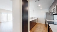 Located at 4550 Lincoln Ave in Cypress, CA, this well-appointed one-bedroom, one-bathroom unit offers a thoughtfully designed layout with consistent light wood flooring throughout. The open-concept kitchen and living area serves as the heart of the unit, featuring a galley-style kitchen outfitted with dark espresso cabinetry, sleek white countertops, stainless steel appliances including a refrigerator, oven, and dishwasher, and pendant lighting that adds a contemporary touch. A tall floor-to-ceiling pantry cabinet provides generous storage. The living room is bright and airy, enhanced by recessed lighting and a large sliding glass door with vertical blinds that floods the space with natural light. A clean, well-lit hallway connects the main living area to the private quarters. The bedroom is a comfortable retreat featuring a window with blinds, and a mirrored sliding-door closet that adds depth and functionality. The bathroom is finished in a clean, modern style with dark wood cabinetry, a white countertop vanity, and a full tub-shower combination with a curved curtain rod. The overall aesthetic is modern and neutral, making for a move-in-ready space with cohesive design elements throughout.