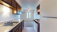 Located at 44825 Mound Rd in Sterling Heights, Michigan, this single-floor unit offers a practical and well-organized layout. The galley-style kitchen is equipped with dark wood cabinetry lining both walls, light-toned countertops, a gas range, a refrigerator, and a built-in sink. Tile flooring runs throughout the kitchen, and a ceiling fan with a window at the far end provides natural light and ventilation. The kitchen transitions into a carpeted living area that benefits from large windows framing views of surrounding trees and greenery, creating a bright and open atmosphere. A secondary carpeted space serves as an additional living or dining area, also featuring generous window placement. The bedrooms are carpeted and well-lit by multiple windows with outdoor views. One bedroom includes direct access to a full bathroom and a dedicated closet. The full bathroom features a dark wood vanity with a light countertop, a large mirror, a tub-shower combination, and tile flooring. A second bathroom offers a similar vanity style with tile flooring. Throughout the unit, neutral wall tones and consistent finishes contribute to a cohesive and functional living environment.