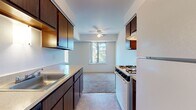Located at 44825 Mound Rd in Sterling Heights, Michigan, this single-floor unit offers a practical and well-organized layout. The galley-style kitchen is equipped with dark wood cabinetry lining both walls, light-toned countertops, a gas range, a refrigerator, and a built-in sink. Tile flooring runs throughout the kitchen, and a ceiling fan with a window at the far end provides natural light and ventilation. The kitchen transitions into a carpeted living area that benefits from large windows framing views of surrounding trees and greenery, creating a bright and open atmosphere. A secondary carpeted space serves as an additional living or dining area, also featuring generous window placement. The bedrooms are carpeted and well-lit by multiple windows with outdoor views. One bedroom includes direct access to a full bathroom and a dedicated closet. The full bathroom features a dark wood vanity with a light countertop, a large mirror, a tub-shower combination, and tile flooring. A second bathroom offers a similar vanity style with tile flooring. Throughout the unit, neutral wall tones and consistent finishes contribute to a cohesive and functional living environment.