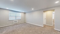 This single-floor, 2-bedroom, 1-bathroom residence offers a practical and comfortable layout designed for efficient living. The combined kitchen and living area serves as the heart of the home, with the kitchen showcasing dark shaker-style cabinetry, white countertops, stainless steel appliances including a gas range and built-in microwave, and a striking blue tile backsplash that adds a bold design element. Tile flooring grounds the kitchen space with a clean, durable finish.

The living area connects seamlessly, featuring neutral-toned carpet and recessed lighting, with a windowed entry door that welcomes natural light. Both bedrooms are carpeted and finished in soft gray tones, each equipped with a wall-mounted air conditioning unit, baseboard heating, and windows with blinds. The primary bedroom offers generous proportions and a closet, while the second bedroom provides a cozy and versatile space.

The bathroom is neatly appointed with a full soaking tub, a vertically tiled surround in layered gray and blue tones, tile flooring, and clean white fixtures, creating a calm and modern aesthetic. A hallway connects all rooms, completing this efficiently designed and move-in ready residence.