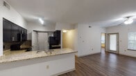 This single-story, 3-bedroom, 2-bathroom residence offers a thoughtfully designed open floor plan that maximizes comfort and functionality. Rich wood-style flooring flows consistently throughout the living areas and bedrooms, creating a cohesive and modern aesthetic.

The kitchen serves as a central hub of the home, featuring a granite-topped peninsula with an undermount sink, dark espresso cabinetry, a subway tile backsplash, and black appliances including a refrigerator. Track lighting illuminates the workspace, and the open layout allows for seamless interaction with the adjoining living area.

The spacious living room is bathed in natural light from large windows with blinds and a glass door that leads to the exterior. A ceiling fan adds comfort to the generous, open space.

Each of the three bedrooms is equipped with its own ceiling fan and window, providing ample natural light and ventilation. Closet storage is included in each room.

The two bathrooms are finished with granite countertops and dark cabinetry. The primary bathroom features a jetted soaking tub with tiled surround, while the secondary bathroom offers a full tub-shower combo, a single-sink vanity with overhead cabinetry, and wood-style flooring. The layout is practical and well-organized throughout.