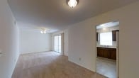 This single-floor, 2-bedroom, 1-bathroom residence offers a well-organized layout designed for comfortable everyday living. The main living area is generously proportioned, featuring soft carpeted flooring, a ceiling fan with light fixture, and a textured ceiling that adds subtle character overhead. A sliding glass door floods the room with natural light and provides direct access to an outdoor area, creating an easy indoor-outdoor connection.

Adjacent to the living space, the kitchen and dining area are conveniently accessible through an open pass-through layout. The kitchen is equipped with warm wood-toned cabinetry, a sink with overhead lighting, and tile flooring that contrasts cleanly with the carpeted living spaces. The practical design ensures efficient use of the available space throughout.

The neutral color palette of white and beige tones throughout the residence creates a clean, move-in-ready canvas that is easy to personalize. The straightforward, functional floor plan allows for flexible furniture arrangements in the main living area, while the ceiling fan supports year-round comfort. Overall, this residence offers a practical and comfortable living environment with key amenities thoughtfully integrated throughout the layout.