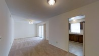 This single-floor, 2-bedroom, 1-bathroom residence offers a well-organized layout designed for comfortable everyday living. The main living area is generously proportioned, featuring soft carpeted flooring, a ceiling fan with light fixture, and a textured ceiling that adds subtle character overhead. A sliding glass door floods the room with natural light and provides direct access to an outdoor area, creating an easy indoor-outdoor connection.

Adjacent to the living space, the kitchen and dining area are conveniently accessible through an open pass-through layout. The kitchen is equipped with warm wood-toned cabinetry, a sink with overhead lighting, and tile flooring that contrasts cleanly with the carpeted living spaces. The practical design ensures efficient use of the available space throughout.

The neutral color palette of white and beige tones throughout the residence creates a clean, move-in-ready canvas that is easy to personalize. The straightforward, functional floor plan allows for flexible furniture arrangements in the main living area, while the ceiling fan supports year-round comfort. Overall, this residence offers a practical and comfortable living environment with key amenities thoughtfully integrated throughout the layout.