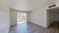 This 2-bedroom, 2-bathroom single-floor unit offers a practical and well-designed layout with clean, neutral finishes throughout. The bright living room features smooth hardwood-style flooring, crisp white walls, and a textured ceiling, with a large sliding glass door that fills the space with natural light and provides direct access to an outdoor area. A ceiling fan in the adjoining area adds both function and airflow to the open living space.

The galley-style kitchen is efficiently designed with white cabinetry, speckled gray laminate countertops, and black appliances including a range and full-size refrigerator, complemented by hardwood-style flooring that extends throughout the common areas.

Both bedrooms are carpeted and feature natural light from windows with blinds. The primary bedroom offers a comfortable footprint with two closets, while the second bedroom includes a ceiling fan and an outdoor view. Each bathroom is clean and functional — one features a white vanity with brushed nickel fixtures, a framed mirror, and overhead lighting, while the other includes a tub-shower combination with white tile surround and updated hardware.

A hallway connects the rooms, creating a logical and easy-to-navigate flow throughout the unit. Overall, the space presents a tidy, move-in-ready environment with consistent finishes and ample natural light.