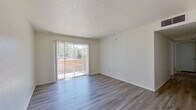 This 2-bedroom, 2-bathroom single-floor unit offers a practical and well-designed layout with clean, neutral finishes throughout. The bright living room features smooth hardwood-style flooring, crisp white walls, and a textured ceiling, with a large sliding glass door that fills the space with natural light and provides direct access to an outdoor area. A ceiling fan in the adjoining area adds both function and airflow to the open living space.

The galley-style kitchen is efficiently designed with white cabinetry, speckled gray laminate countertops, and black appliances including a range and full-size refrigerator, complemented by hardwood-style flooring that extends throughout the common areas.

Both bedrooms are carpeted and feature natural light from windows with blinds. The primary bedroom offers a comfortable footprint with two closets, while the second bedroom includes a ceiling fan and an outdoor view. Each bathroom is clean and functional — one features a white vanity with brushed nickel fixtures, a framed mirror, and overhead lighting, while the other includes a tub-shower combination with white tile surround and updated hardware.

A hallway connects the rooms, creating a logical and easy-to-navigate flow throughout the unit. Overall, the space presents a tidy, move-in-ready environment with consistent finishes and ample natural light.
