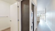 Located in Berkeley, CA (94702), this single-floor unit offers a thoughtfully designed open layout with modern finishes throughout. The wood-style flooring runs continuously across the living and kitchen areas, lending warmth and cohesion to the space.

The kitchen is well-appointed with stainless steel appliances, including a range, over-the-range microwave, dishwasher, and refrigerator. Light wood cabinetry pairs with a clean white quartz countertop and a subway tile backsplash, giving the space a bright, contemporary feel. A pass-through counter connects the kitchen to the adjacent living area, enhancing the open-concept flow and allowing natural light from the windows to reach deeper into the unit.

The living area is generously sized with a wide window that brings in outdoor views and natural light. A built-in slatwall panel provides practical organization for storage hooks and accessories. The open layout also accommodates a flexible dining or multi-use area.

The bathroom features a wood-toned vanity with a white countertop, an undermount sink, brushed nickel fixtures, and a framed mirror — all set against light tile flooring and neutral walls for a clean, spa-like aesthetic.

A dedicated hallway closet houses a stacked washer and dryer unit behind louvered sliding doors, offering in-unit laundry convenience. The overall design emphasizes functionality, natural light, and modern simplicity.