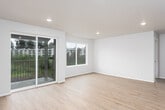 This single-floor residence is designed with a clean, contemporary aesthetic defined by a neutral white and light wood palette throughout. The open-concept layout connects the kitchen and living area into one cohesive, light-filled space. The kitchen is well-appointed with white shaker-style cabinetry, light quartz countertops, a central island, and a full suite of stainless steel appliances including a refrigerator, range, microwave, and dishwasher. Recessed lighting illuminates the space, and light wood-tone laminate flooring extends throughout the entire unit, contributing to a seamless, airy feel.

The living area benefits from abundant natural light provided by large windows and a sliding glass door that opens onto a private balcony overlooking greenery. Multiple bedrooms are generously sized, each featuring wide windows with outdoor views. One bedroom includes a sliding double-door closet, while another offers direct access to an en suite bathroom. The bathroom features a full soaking tub and shower combination with brushed nickel fixtures and clean white tile surround. Overall, the space presents a modern, move-in ready environment with a bright and open ambiance.