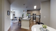 This single-story 1-bedroom, 1-bathroom residence at 800 Timber Valley Way in Oakwood, GA offers a thoughtfully designed open-concept layout finished with contemporary details throughout. Rich wood-look flooring flows continuously across the main living areas, grounding the space with warmth and visual continuity.

The kitchen serves as the centerpiece of the home, featuring light wood cabinetry, dark countertops, a white subway tile backsplash, and a full suite of stainless steel appliances including a range, microwave, and dishwasher. A white island with a dark countertop provides additional prep space and bar seating, illuminated by two pendant lights with brushed nickel fixtures. The kitchen connects seamlessly to the dining and living areas, making the overall layout ideal for daily living and entertaining.

The living room is bright and comfortable, featuring a ceiling fan, large windows that allow natural light to fill the space, and neutral walls that create a calm, versatile backdrop.

The bedroom is generously sized with tall ceilings, wood-look flooring, and direct access to a walk-in closet. The bathroom features a full walk-in shower enclosed by sliding glass doors, accented with white subway tile and brushed nickel hardware. An in-unit laundry area is also present, adding everyday convenience.
