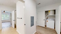 This thoughtfully designed 2-bedroom, 1-bathroom residence in Danbury, CT offers a clean, modern aesthetic throughout its single-floor layout. Light wood-style flooring flows consistently across all rooms, creating a cohesive and bright atmosphere.

The kitchen is a standout feature, boasting rich warm-toned cabinetry with sleek dark hardware, white countertops, and a full suite of black appliances including a range with overhead ventilation and a built-in microwave. Generous upper and lower cabinet storage provides excellent functionality in a well-organized U-shaped configuration.

The combined kitchen and living area is open and airy, with natural light streaming through large windows fitted with white horizontal blinds, offering views of surrounding greenery. Sliding glass doors lead to an outdoor space, further enhancing the sense of openness.

The spacious primary bedroom includes a ceiling fan, a closet, and a window with outdoor views. The second bedroom is comfortably sized, also featuring a closet and natural light from a window. Both rooms maintain the clean white walls and light flooring found throughout the unit.

The bathroom is finished with warm wood cabinetry, a wide vanity mirror, white countertops, and a full soaking tub with shower combination, all set on neutral tile flooring for a clean, classic look.
