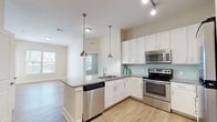 Located at 711 Beach Blvd in Jacksonville Beach, Florida, this 2-bedroom, 2-bathroom residence offers a well-designed single-floor layout with a bright, coastal-inspired aesthetic. The open-concept kitchen and living area serves as the heart of the home, featuring a large peninsula with granite countertops and pendant lighting, white shaker-style cabinetry, a light blue subway tile backsplash, and a full suite of stainless steel appliances including a dishwasher, range, microwave, and refrigerator. Light wood-style flooring flows throughout the main living areas, complementing the neutral color palette and creating a clean, modern feel. Natural light fills the space through multiple windows. The primary bedroom offers comfortable proportions with plush carpeting, a dedicated closet with wire shelving systems, and a private en-suite bathroom featuring a double-sink granite vanity, white cabinetry, and a glass-enclosed walk-in shower. The second bedroom is equally well-appointed with carpeted floors and natural window light. The second bathroom mirrors the quality finishes of the primary, with a granite vanity and a tub-shower combination. Two dedicated closets provide ample storage throughout the residence. A private entry door with transom window adds a welcoming touch to this thoughtfully designed Jacksonville Beach home.