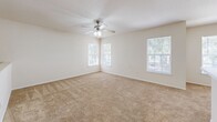 Located in Orlando, FL, this two-story, 2-bedroom, 2-bathroom home offers a practical and comfortable layout spread across two levels. The entry level features a carpeted staircase with a handrail leading up to the main living floor, where the majority of the home's space is found. The open-concept kitchen and living area serves as the heart of the home, with the kitchen equipped with wooden cabinetry, a white appliance package including a range and refrigerator, a double sink, and wood-look flooring that extends throughout the common areas. The living space transitions seamlessly from the kitchen, providing a functional and connected layout. Both bathrooms feature warm wood-toned vanities with stone-look countertops, wood-look tile flooring, and full shower-tub combinations. The bedrooms are carpeted and generously sized, with the primary bedroom offering corner windows that allow ample natural light and a ceiling fan overhead. Multiple walk-in closets with wire shelving systems provide excellent storage throughout. With five closets total and a dedicated laundry area, this home prioritizes practical storage and organization. The neutral color palette and clean finishes create a bright, move-in ready environment.
