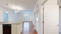 Located at 3113 Pine Orchard Lane in Ellicott City, MD, this well-designed two-bedroom, two-bathroom single-floor residence offers a bright and functional layout. The open-concept living area features gleaming hardwood flooring and large windows with blinds that bathe the space in natural light, with direct access through a full-light entry door. The kitchen is outfitted with granite countertops, white cabinetry, pendant lighting, a double sink, and black appliances including a refrigerator and dishwasher, flowing seamlessly into the dining and living areas. The primary bedroom is a comfortable, well-proportioned retreat with plush carpeting, a bright window, and access to a spacious walk-in closet with wire shelving. The second bedroom also features soft carpeting and a generously sized window with views of surrounding greenery. Both bathrooms are clean and functional, with one featuring a full tub-shower combo, white tile surround, a dark wood vanity with white countertop, and tile flooring. Three closets throughout provide ample storage. The overall aesthetic is clean, neutral, and move-in ready, with consistent finishes creating a cohesive and comfortable living environment.