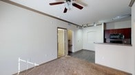 This single-floor, 1-bedroom, 1-bathroom residence offers a practical and comfortable layout designed to maximize livability. The main living area is anchored by plush carpeting and features a ceiling fan with integrated lighting, providing both comfort and illumination throughout the space. Elegant crown molding runs along the upper perimeter of the walls, adding a refined architectural detail to the interior.

Transitioning from the living area, the flooring shifts to a durable hardwood-style surface, which extends toward the kitchen and dining areas. The kitchen is equipped with track lighting overhead and features a raised bar-height counter that opens toward the living space, creating a connected and sociable atmosphere. Arched doorways throughout the unit lend a classic architectural character, softening the transitions between rooms.

Neutral wall tones in a warm off-white palette provide a clean, versatile backdrop that complements a variety of décor styles. The layout provides a clear sightline from the living area through to the kitchen, enhancing the sense of openness. Overall, this residence combines functional design elements with tasteful architectural touches to create a welcoming and well-appointed living environment.