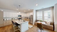 Located at 2410 Smith Gln Rd in Charlotte, NC, this thoughtfully designed one-bedroom, one-bathroom residence offers a cohesive and functional single-floor layout. The open-concept kitchen and living area serves as the heart of the home, featuring a large center island with granite countertops and bar seating, crisp white upper cabinetry, contrasting warm-toned lower cabinets, a herringbone tile backsplash, stainless steel appliances, and pendant lighting. Recessed lighting and a nearby window fill the space with natural light.

The living room is bright and welcoming, with large windows framing lush outdoor greenery, sheer curtains, and a ceiling fan that enhances the airy atmosphere. Warm hardwood-style flooring flows seamlessly throughout the entire unit, tying each space together.

The bedroom is a comfortable retreat, bathed in natural light from generous windows with views of surrounding trees. A ceiling fan adds to the relaxed ambiance, while neutral tones and ample wall space create a calm, versatile environment.

The bathroom features a clean, functional design with a full tub-shower combination and neutral finishes. Every room reflects a modern, understated aesthetic that balances style and practicality in this Charlotte residence.
