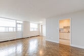Located at 1257 Lakeshore Rd E in Mississauga, this well-laid-out 2-bedroom, 1-bathroom unit offers a practical and comfortable single-floor living arrangement. The space is defined throughout by warm parquet wood flooring in a classic basket-weave pattern, lending character and continuity across the living room, bedrooms, and hallway.

The living room is an open, airy space highlighted by large windows that bring in generous natural light and offer elevated views of the surrounding neighbourhood. Baseboard heating runs along the perimeter, ensuring warmth throughout the seasons. The kitchen is efficiently designed with modern stainless steel appliances, including an electric range with an over-the-range microwave, and features tile flooring and white cabinetry. It connects directly to the living area through an open pass-through for easy flow.

The spacious primary bedroom includes a closet and benefits from corner windows framing outdoor views. The second bedroom is well-sized with its own closet and parquet flooring. The bathroom is clean and updated, featuring a tiled shower-tub combination with white subway tiles accented by a grey ceramic border strip and chrome fixtures. A hallway with additional closet space completes the layout, providing practical storage throughout.