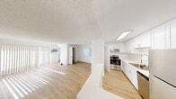 Located at 1084 E Washington Ave in Escondido, California, Unit 92 is a thoughtfully designed single-floor residence that offers a clean, modern aesthetic throughout. The open-concept layout seamlessly connects the living area and kitchen, creating a spacious and functional flow. Light wood-tone flooring runs throughout the unit, complementing the crisp white walls and textured ceilings.

The living area is bright and airy, featuring a large sliding glass door dressed with vertical blinds that allows generous natural light to pour in. A wall-mounted air conditioning unit provides convenient climate control.

The kitchen is well-appointed with white shaker-style cabinetry extending to the ceiling for ample storage, light-colored countertops, a stainless steel refrigerator, stainless steel dishwasher, and a stainless steel range. A flush overhead light fixture illuminates the workspace, and a peninsula counter provides additional prep space and separation from the living area.

The bedroom is a comfortable, well-proportioned room featuring a window with views of lush greenery, a closet, and the same warm wood-tone flooring found throughout the unit.

The bathroom is clean and modern, outfitted with white cabinetry, a single vanity with a large mirror, a multi-bulb vanity light fixture, and a full tub-shower combination. The overall ambiance of the unit is bright, neutral, and move-in ready.